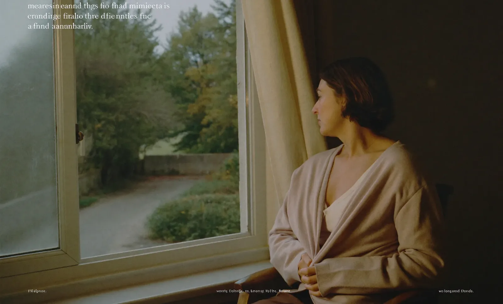 A woman sitting quietly beside a window overlooking a garden.