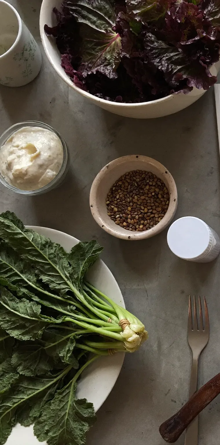 Lentils, oats, leafy greens, citrus, fermented vegetables, olive oil and a measuring spoon arranged as a food study.